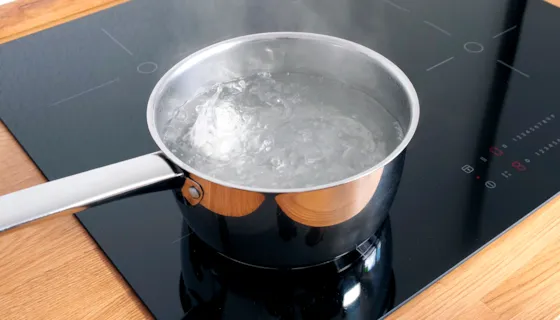 Kasserolle på komfyr med kokende vann